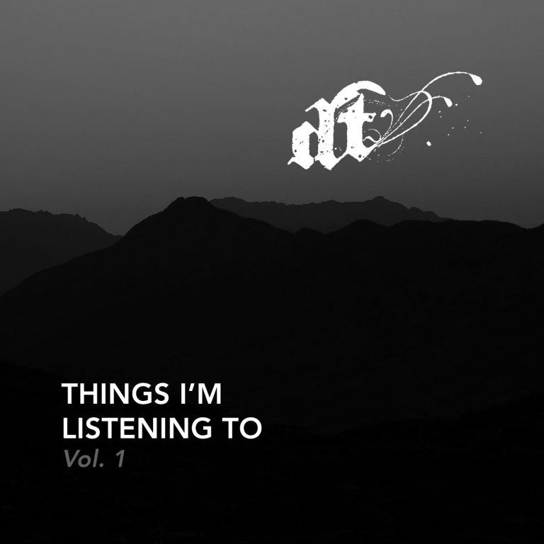 A monochromatic image features a dark, silhouetted mountain range or hills against a lighter gray sky. In the upper center, a stylized white gothic 'dt' with ink splatters and flowing lines extends to the right. In the lower-left corner, white text reads "THINGS I'M LISTENING TO" and below it, "Vol. 1" in a slightly lighter gray.